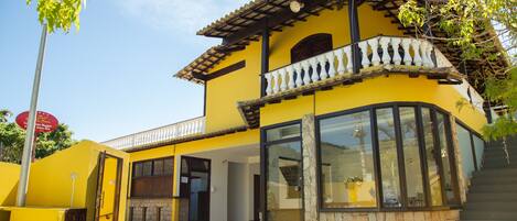 A yellow building with a swimming pool, a balcony, and a stone wall.