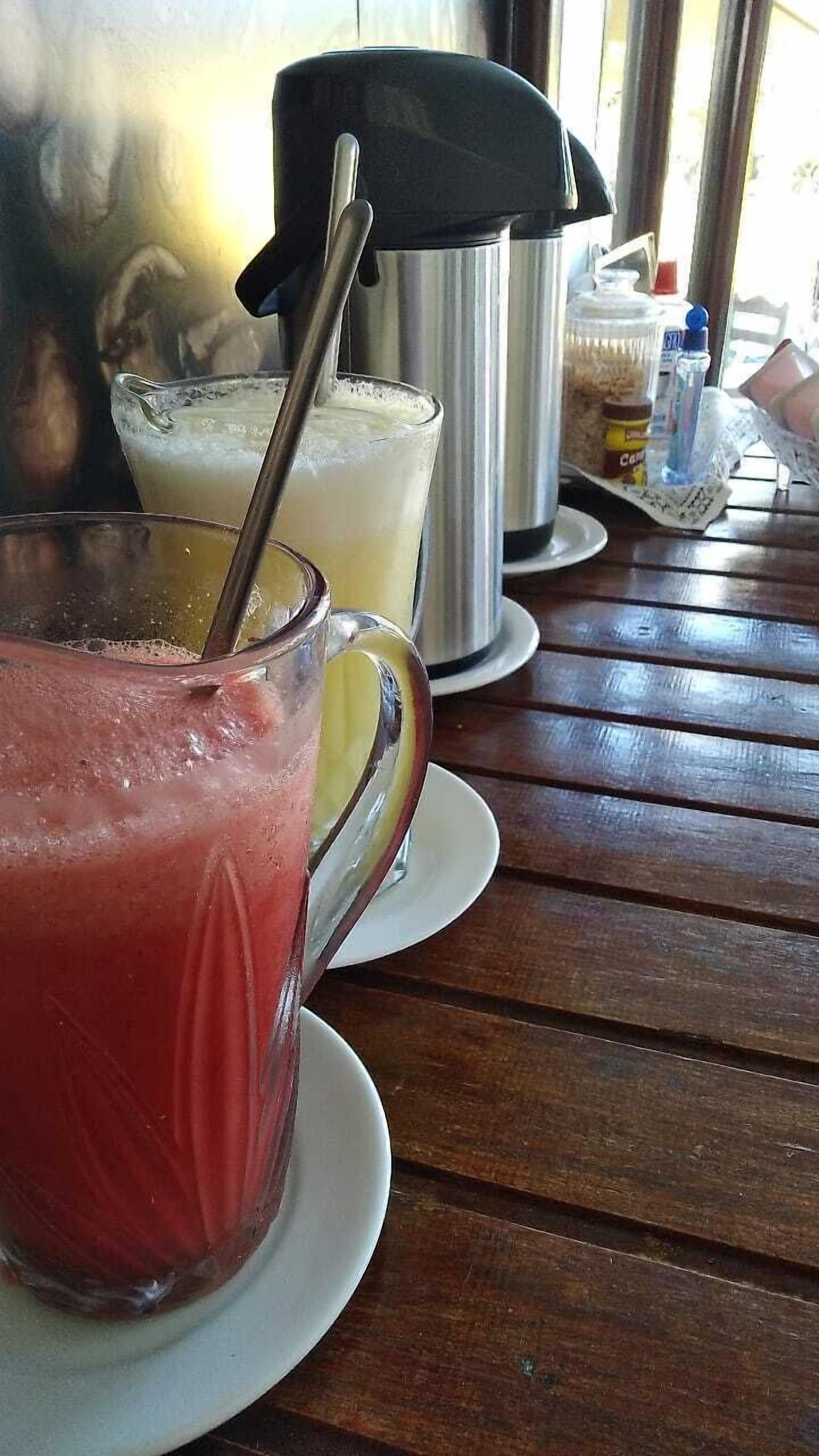 Una mesa con dos vasos de bebidas, uno con pajita y otro sin ella.