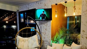Un salón moderno con un sillón colgante, un sofá redondo, un televisor de pantalla plana y una lámpara fijada a la pared.