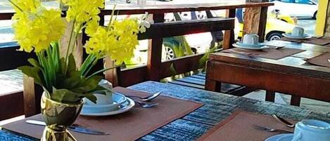 A table with a vase of yellow flowers, a plate, and a spoon.