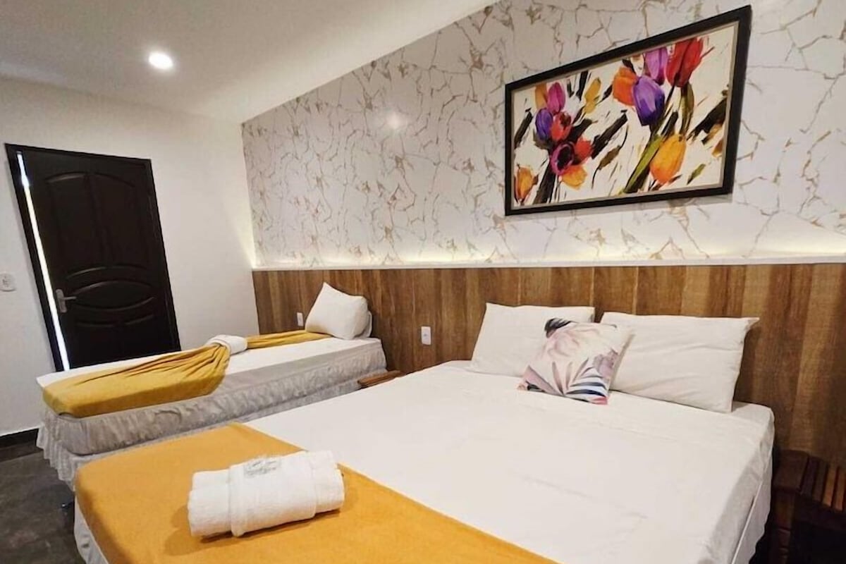A hotel room with two beds, a wooden headboard, a painting, and a door.