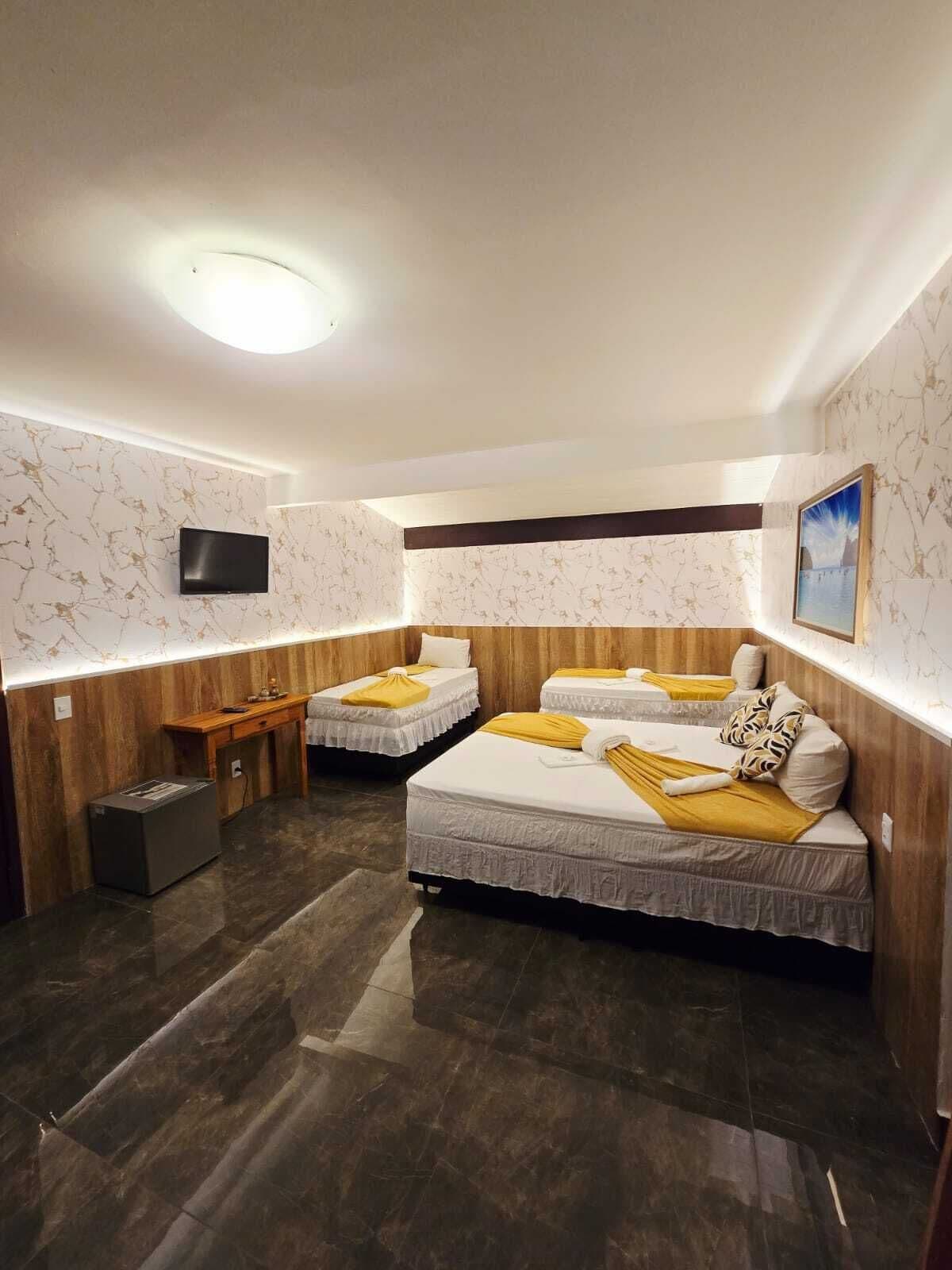 A hotel room with two beds, a TV, a desk, and a small trash bin.
