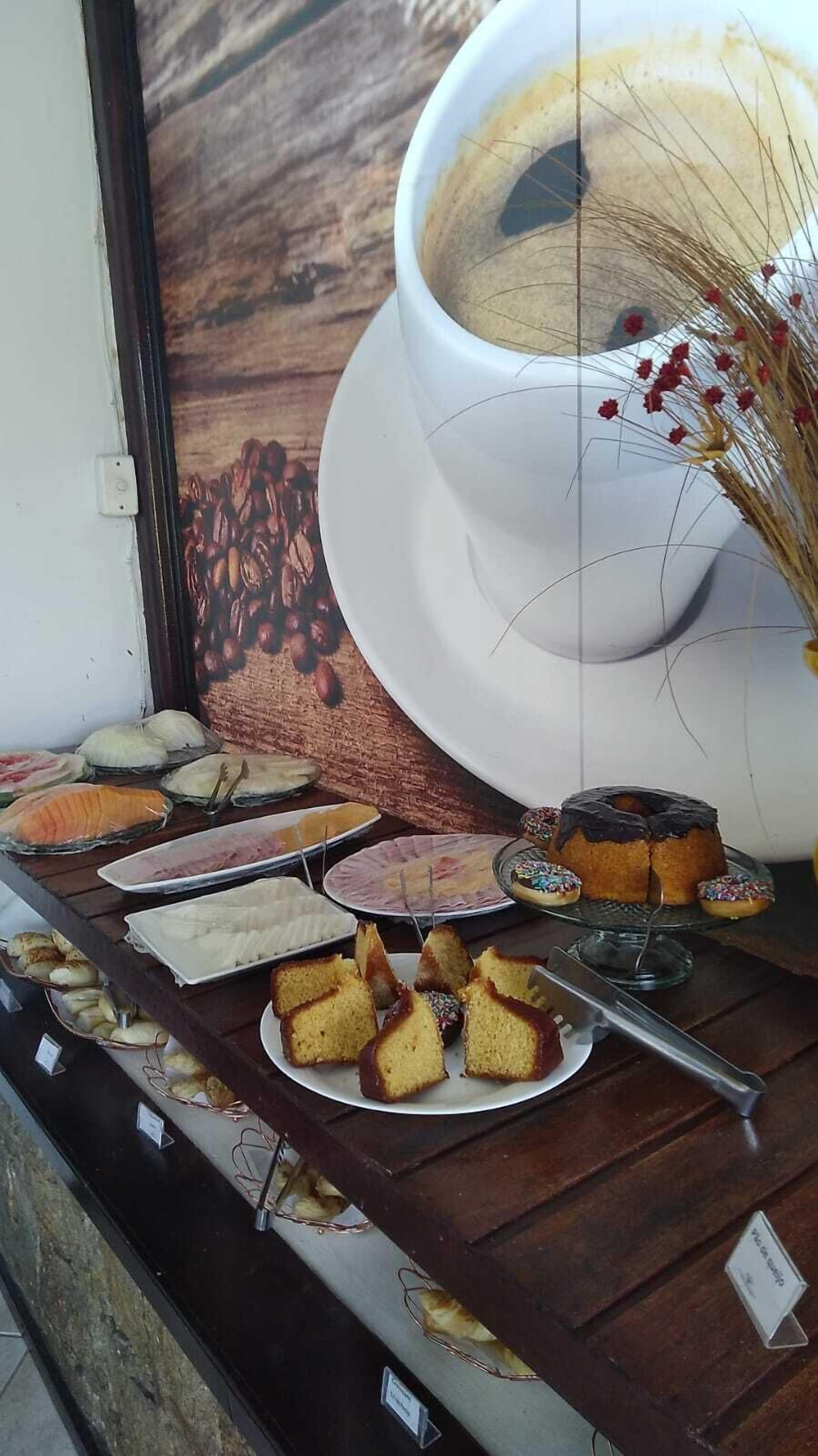 A display of various baked goods and pastries, including cakes and cookies, arranged on a wooden counter with a rustic backdrop.