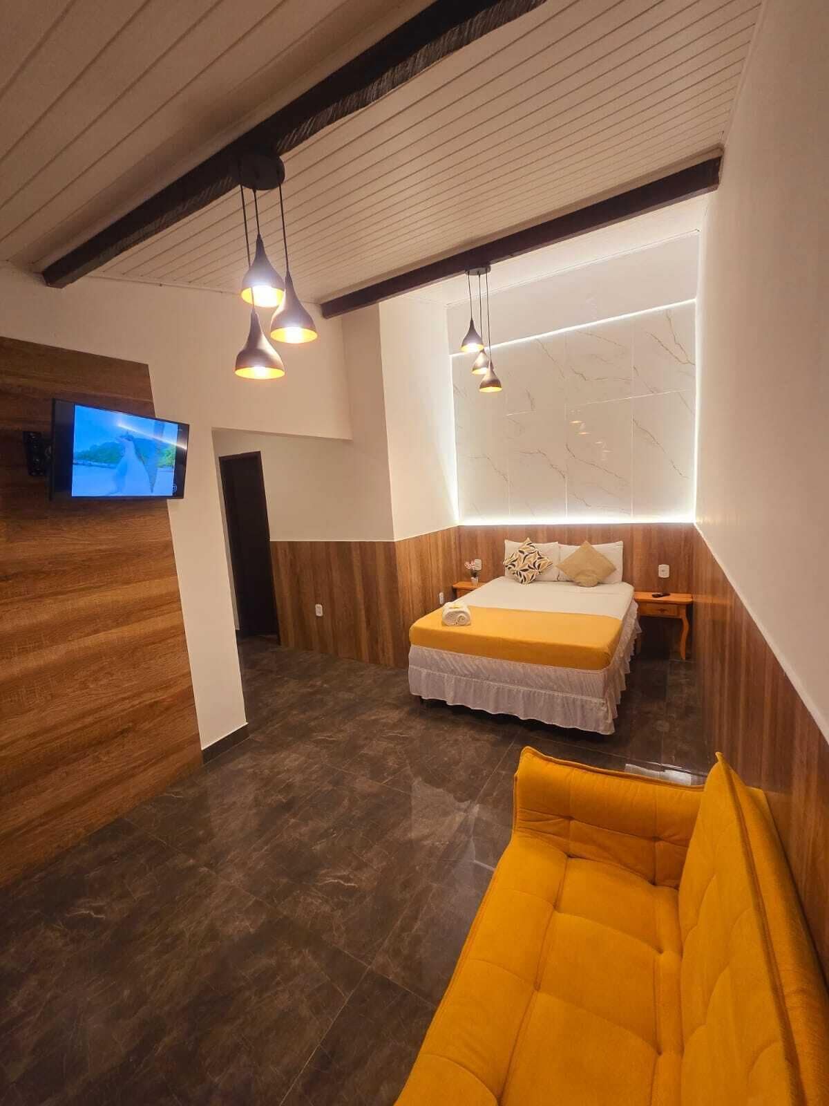 Una habitación de hotel moderna con una cama, un televisor y un sofá.