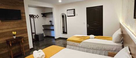 Habitación de hotel con dos camas, una pared de acento de madera, una mesita con un florero y un espejo.