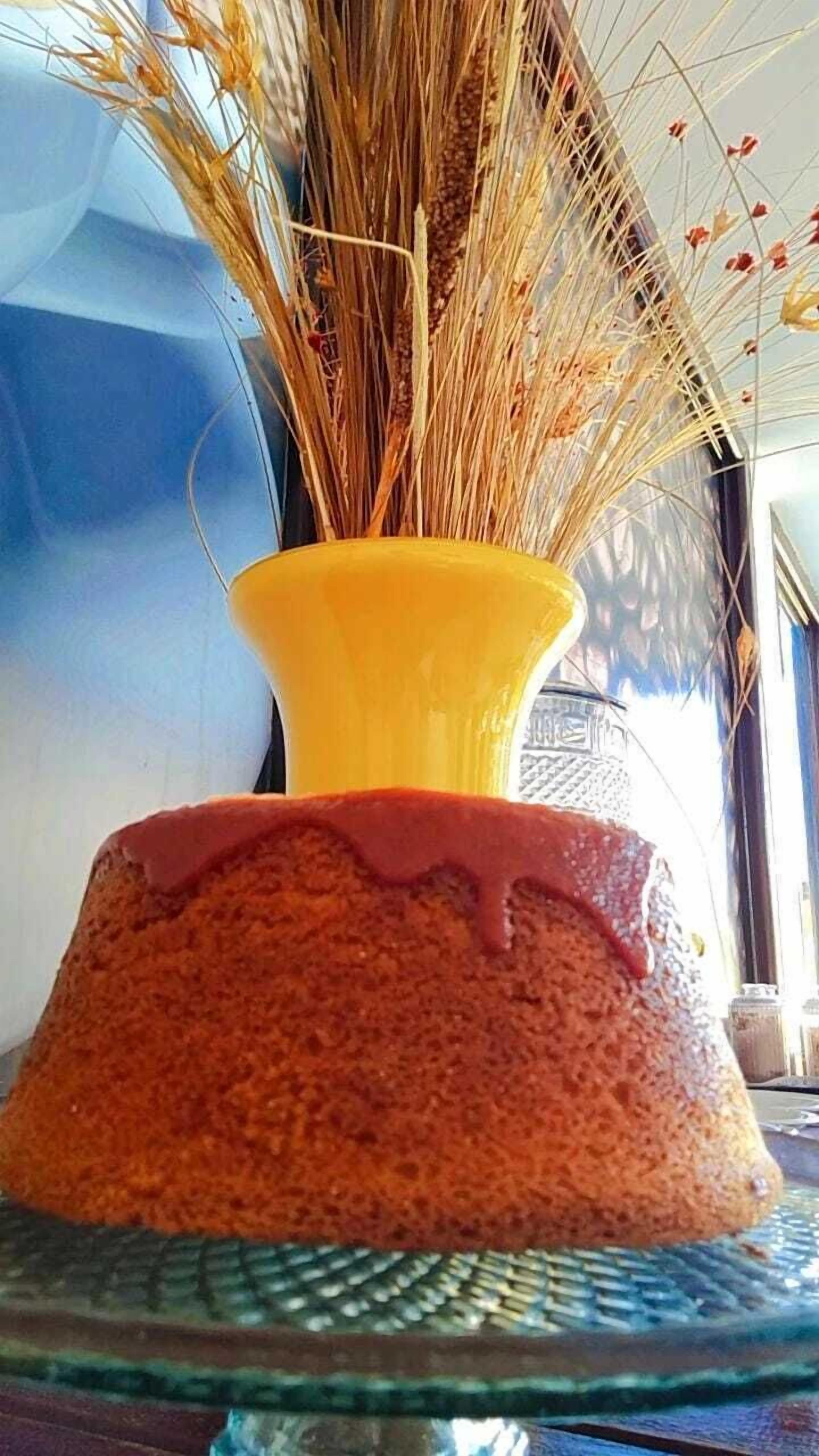 Ein Kuchen mit einer gelben Vase auf einer Glasplatte.