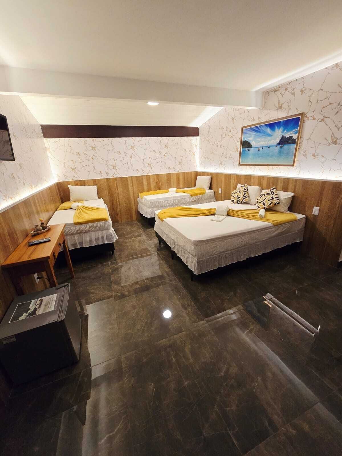 A hotel room with two beds, a wooden desk, a small table, a framed picture on the wall, and a marble floor.