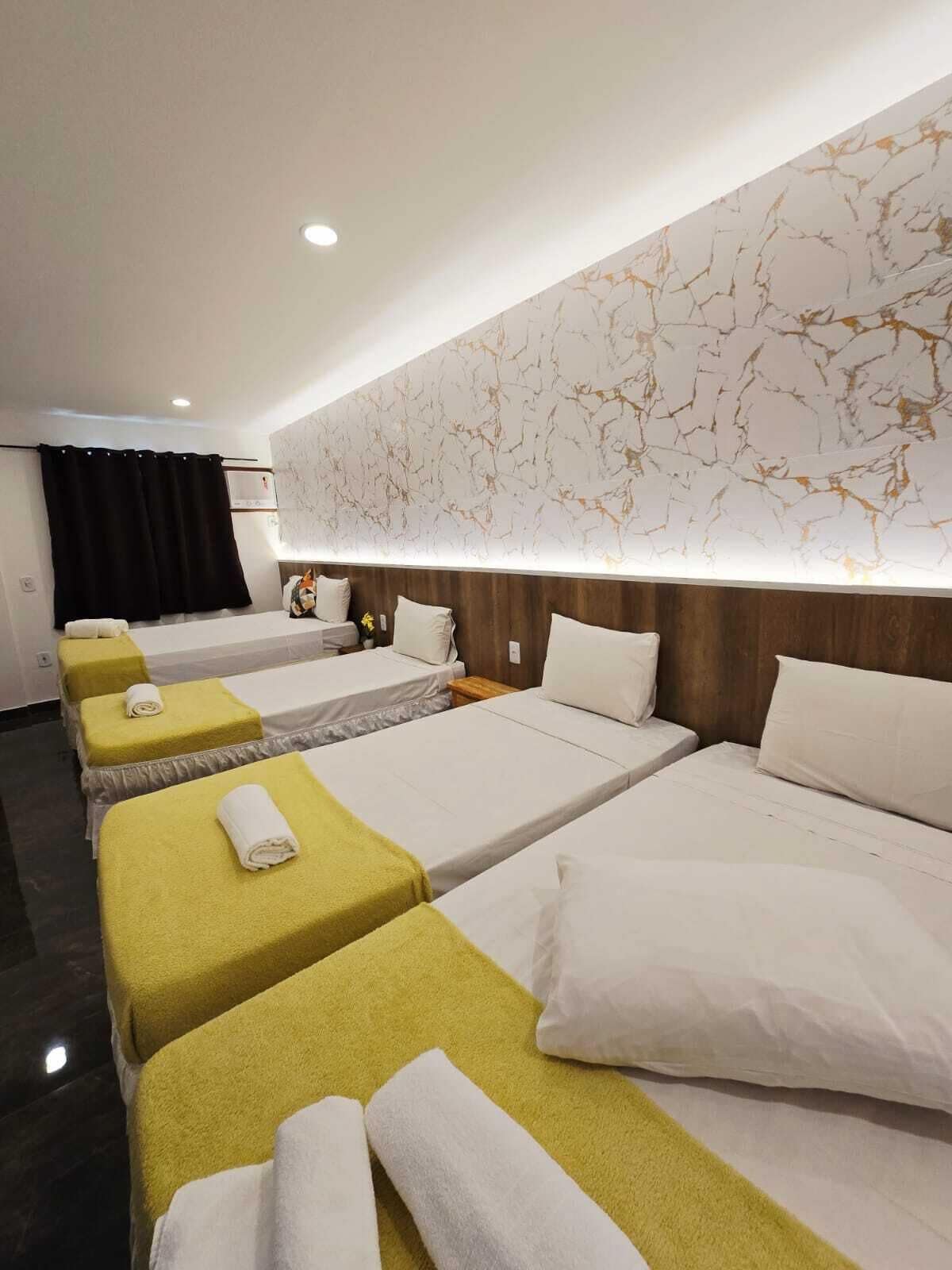 Una habitación de hotel con cuatro camas, un revestimiento de pared con diseño de mármol y un estilo moderno.