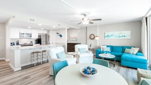 A modern living room with a blue sofa, white armchairs, and a round table. - Sandcastle Condominium Unit 329 (Port Aransas)