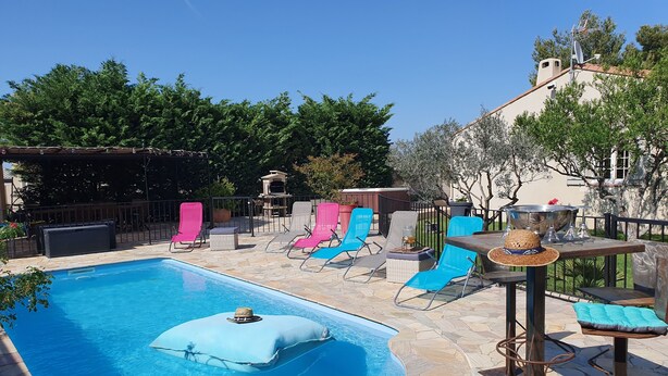 Una piscina con sillas de descanso, una mesa con un sombrero y un patio con baldosas de piedra.