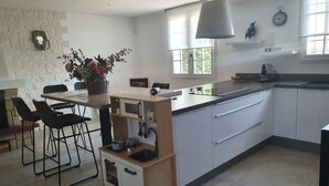 Una cocina moderna con una isla central, muebles blancos y una zona de comedor con sillas.
