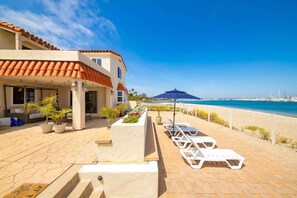 A hotel with a terrace, lounge chairs, and a view of the sea. - On The Beach Casa- with private bay access. (San Diego)