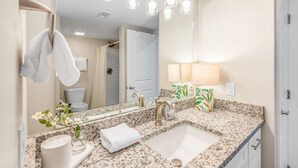 Une salle de bain avec un comptoir en granit, un lavabo, un miroir et un porte-serviettes.