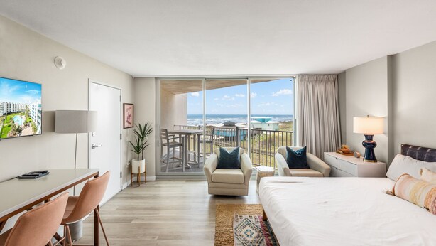 Une chambre d’hôtel équipée d’un lit, d’un bureau, d’une chaise, d’un balcon avec vue et d’une télévision.