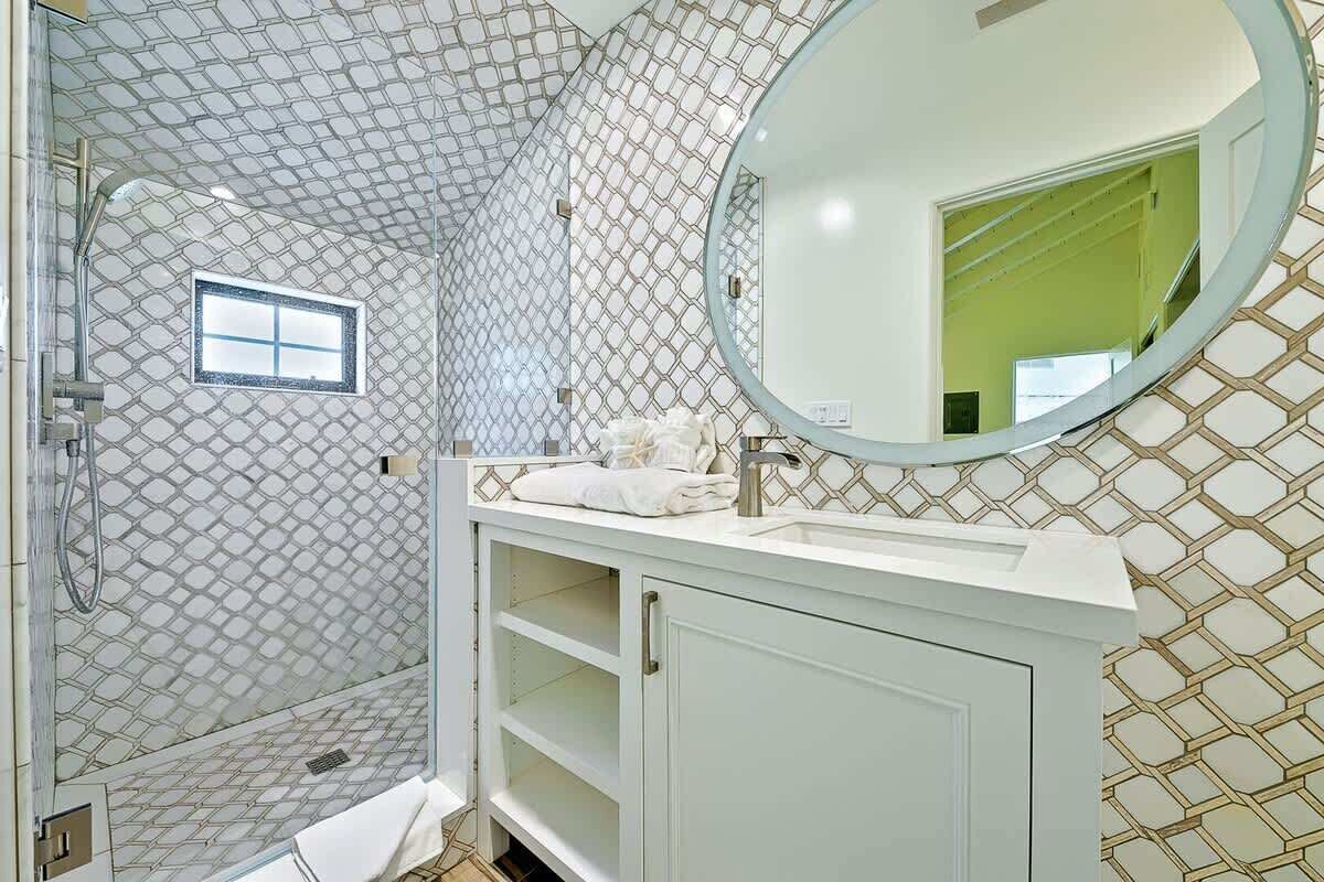 Une salle de bain avec une douche, un lavabo avec un miroir et une fenêtre.