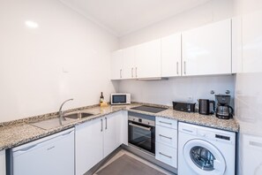 Cocina compacta con lavavajillas, horno, microondas y cafetera.