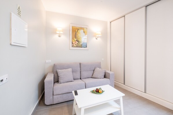 Una sala moderna con un sofá gris, una mesa de centro blanca y un cuadro en la pared.