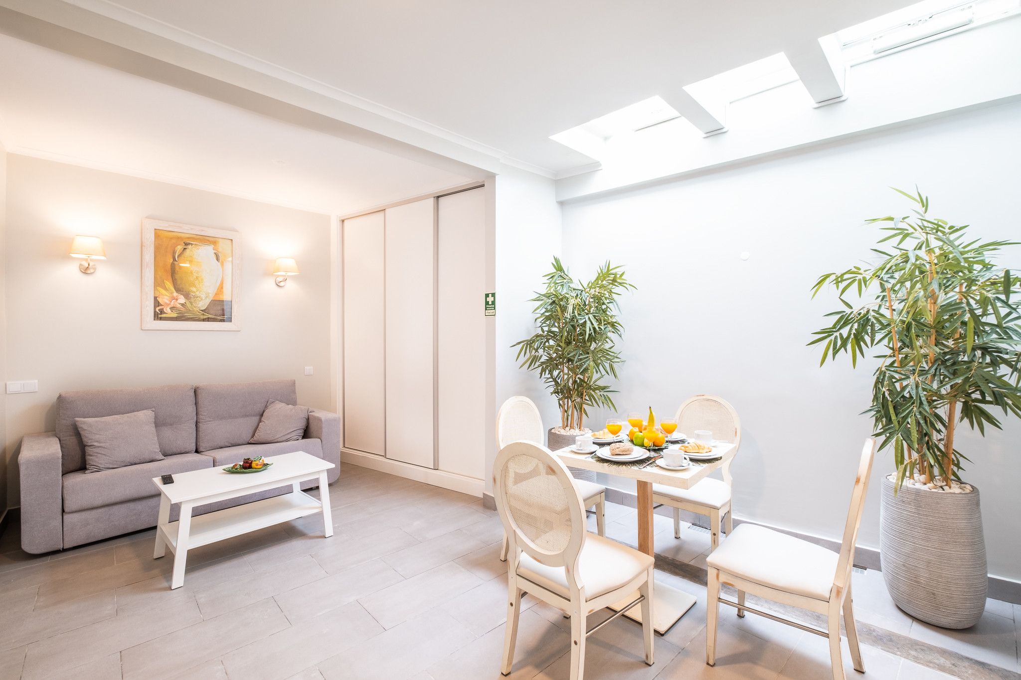 A modern living room with a sofa, coffee table, and dining area with chairs and a table set for breakfast.