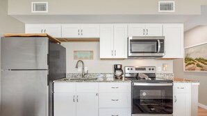 A modern kitchen with white cabinets, stainless steel appliances, a granite countertop, and a built-in oven.