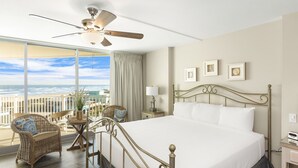 Ein Hotelzimmer mit einem großen Bett, einem Deckenventilator, Meerblick, Korbmöbeln und gerahmten Bildern an der Wand.