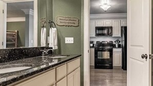A kitchen with a granite countertop, white cabinets, a stainless steel oven, and a microwave.