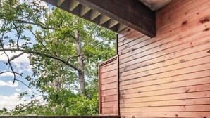 A hot tub on a wooden deck with a view of trees.