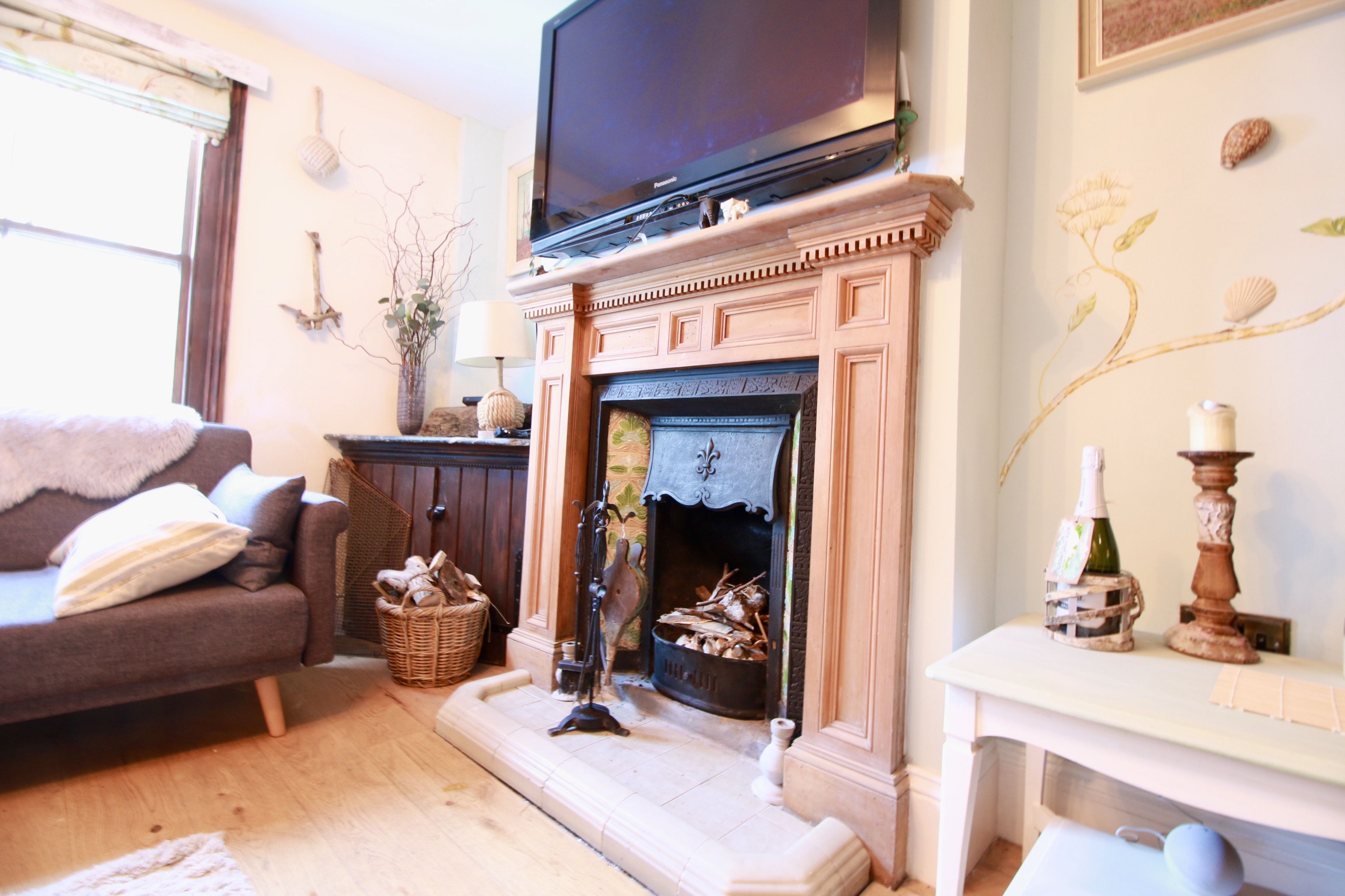 A living room with a fireplace, a television mounted above it, a sofa, and a decorative wall.