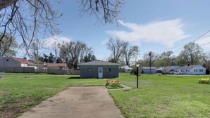 Una propiedad residencial con un camino de entrada pavimentado que conduce a una casa pequeña.