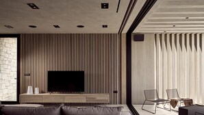 Una sala de estar moderna con un televisor de pantalla plana grande, un sofá y una mesa de centro.