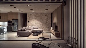 Una sala de estar moderna con una pared de piedra, un sofá, una mesa de centro y un televisor.