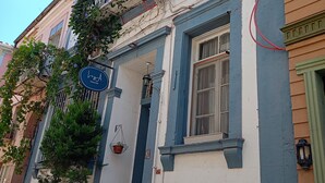 A building with a blue and white facade, a balcony with a red flag, and a sign indicating a room number. - Ayvalık Leya Pansiyon (Ayvalik)