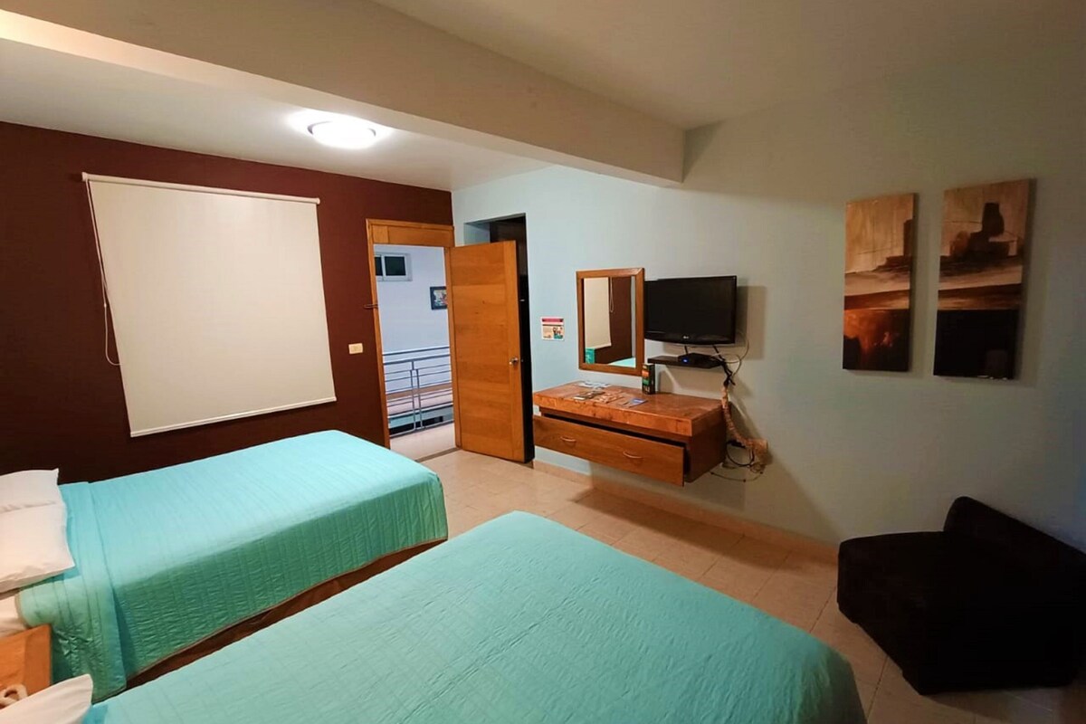 Een kamer met twee bedden, een televisie, een kapstok en een deur naar een balkon.