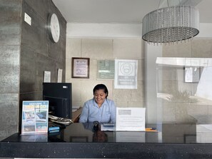 A reception desk with a clock, framed certificates, and a sign indicating mandatory face masks. - Hotel Santo Domingo (Villahermosa)