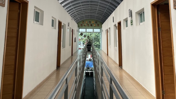 A corridor with a curved metal ceiling, wooden doors, and a central staircase. - Hotel Santo Domingo (Villahermosa)