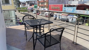 A balcony with two metal tables and chairs, overlooking a street with various buildings and parked cars. - Hotel Santo Domingo (Villahermosa)