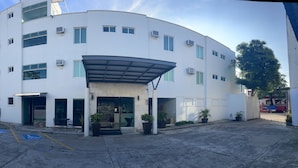A multi-story building with a covered entrance, wheelchair-accessible parking, and air conditioning units. - Hotel Santo Domingo (Villahermosa)