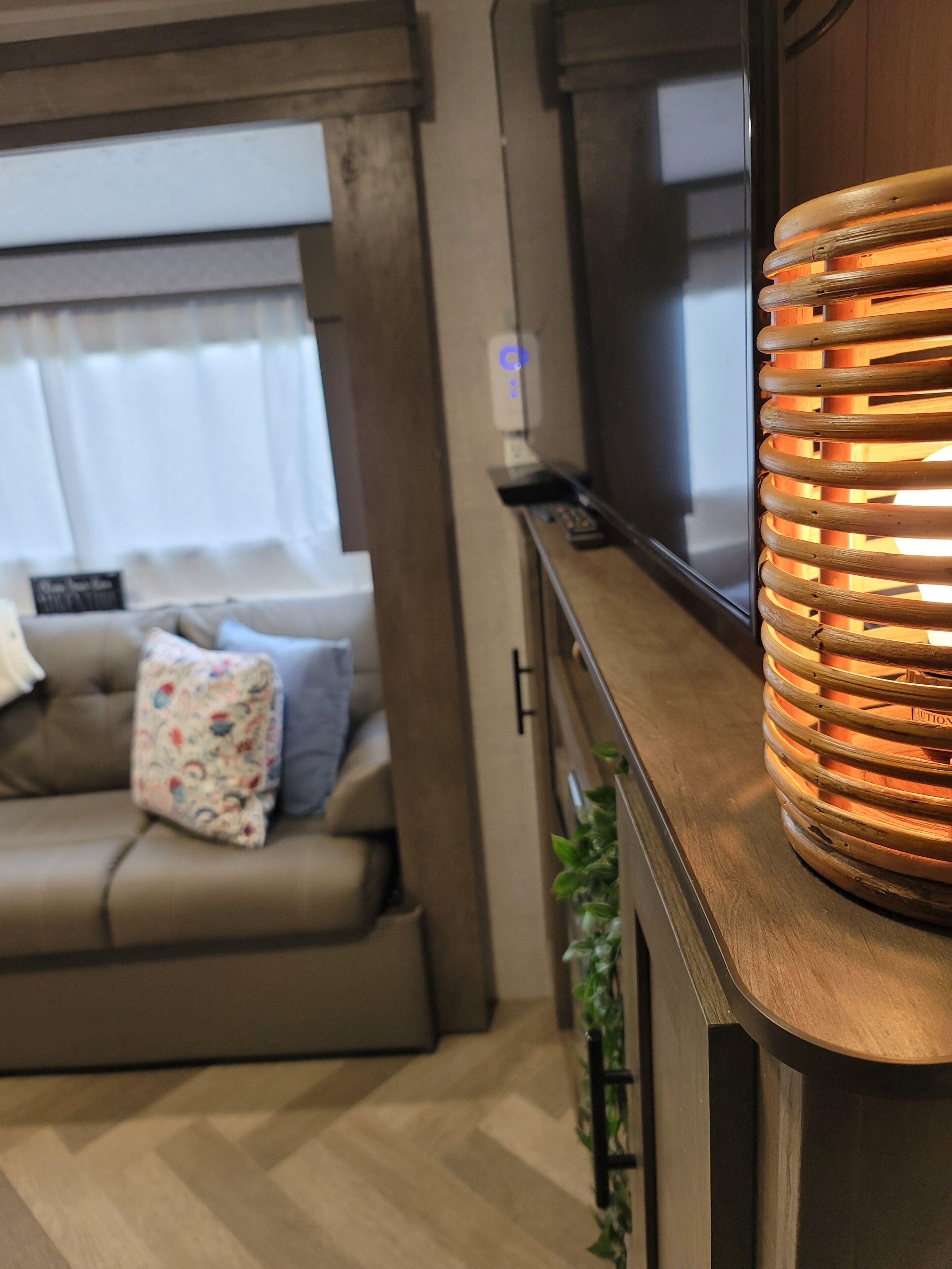 Un salon confortable avec un canapé, un téléviseur et une petite table en bois sur laquelle se trouve une lampe.