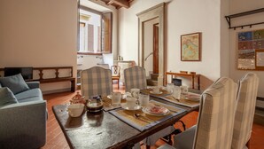Un coin repas avec une table en bois dressée pour quatre personnes, entourée de chaises à motifs à carreaux.