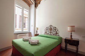 Hotellihuone, jossa on sänky, ikkuna, yöpöytä ja lamppu.