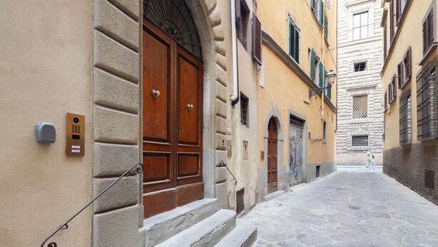 Une ruelle étroite, avec des marches de pierre menant à une porte en bois dotée d’une poignée en laiton.
