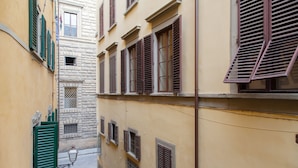 Une ruelle étroite, située entre des immeubles dotés de nombreuses fenêtres et de volets.