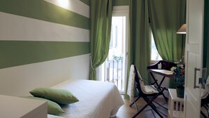 A room with a bed, a desk with a chair, and a balcony with green curtains. - Santa Reparata in Firenze (Florence)