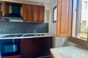 A kitchen with wooden cabinets, a stainless steel sink, and a built-in oven.