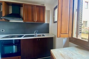 Une cuisine compacte dotée d’une cuisinière intégrée, d’un évier et d’armoires en bois.