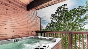 A hot tub on a wooden deck with a view of trees.