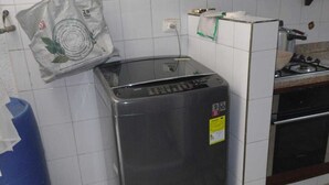 Una cuina compacta amb nevera, fogó de gas i un paper basurero blau.