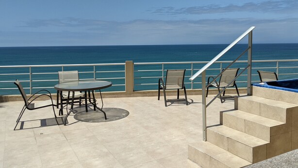 Une terrasse avec piscine, des sièges d’extérieur et une vue sur l’océan.