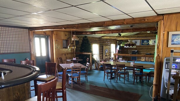 Een restaurant met houten inrichting, meerdere tafels en stoelen, en een bar.