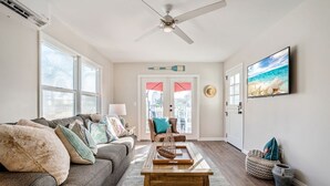 A living room with a gray sofa, a wooden coffee table, and a television on the wall. - "SHORE BREAK" HOUSE... Where Turf Meets Surf! (Oceanside)