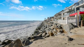 A beachfront hotel with a rocky shoreline, a white fence, and a clear blue sky. - "SHORE BREAK" HOUSE... Where Turf Meets Surf! (Oceanside)